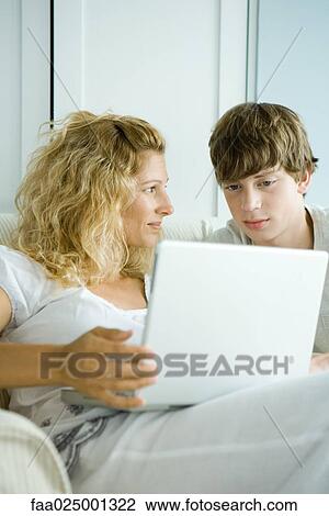 Woman and teen son using laptop View Large Photo Image Stock Image - Woman and teen son using laptop. Fotosearch