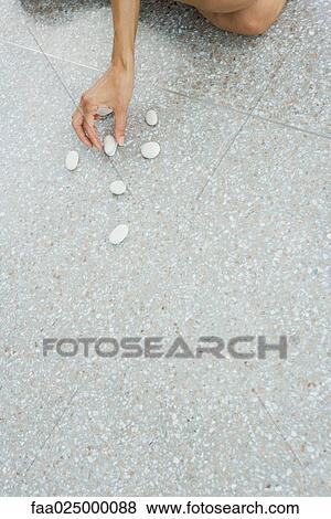 Woman arranging pebbles on the ground, cropped view of hand View Large Photo Image Stock Photo - Woman arranging pebbles on the ground, cropped view of hand. Fotosearch