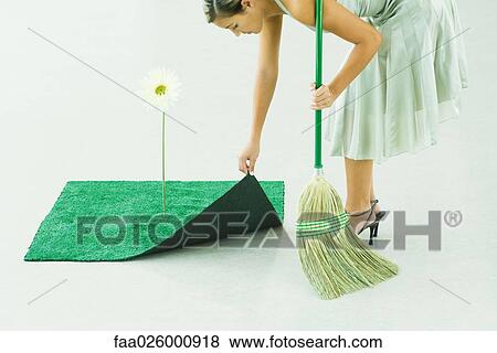 Woman bending over, broom in hand, lifting corner of artificial turf next to gerbera daisy View Large Photo Image Stock Photo - Woman bending over, broom in hand, lifting corner of artificial turf next to gerbera daisy. Fotosearch
