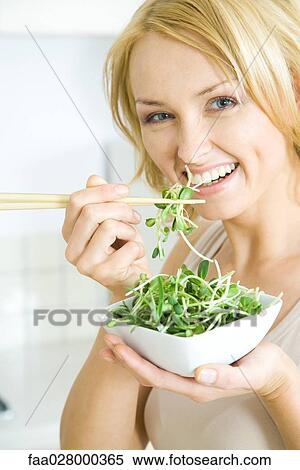 Woman eating radish sprouts with chopsticks, smiling at camera View Large Photo Image Stock Photography - Woman eating radish sprouts with chopsticks, smiling at camera. Fotosearch