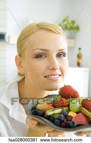 Woman holding assorted fruits on plate, smiling at camera View Large Photo Image Stock Image - Woman holding assorted fruits on plate, smiling at camera. Fotosearch