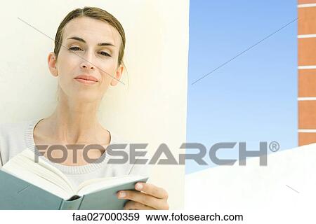 Woman holding book, smiling at camera View Large Photo Image Stock Photo - Woman holding book, smiling at camera. Fotosearch