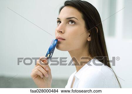 Woman holding credit card up to face, looking up, portrait View Large Photo Image Picture - Woman holding credit card up to face, looking up, portrait. Fotosearch