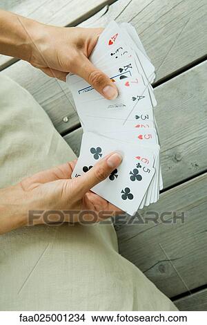 Woman holding deck of cards splayed in hands, cropped view View Large Photo Image Picture - Woman holding deck of cards splayed in hands, cropped view. Fotosearch