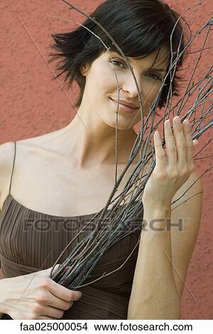 Woman holding dry branches, smiling at camera View Large Photo Image Picture - Woman holding dry branches, smiling at camera. Fotosearch