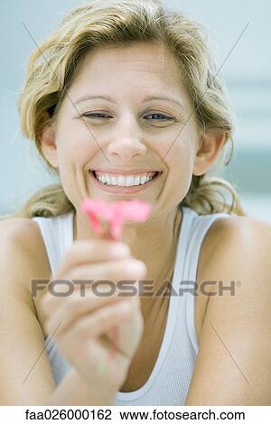 Woman holding flower, smiling, selective focus View Large Photo Image Stock Image - Woman holding flower, smiling, selective focus. Fotosearch