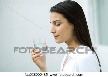 Woman holding glass of water, looking down, side view View Large Photo Image Stock Photography - Woman holding glass of water, looking down, side view. Fotosearch