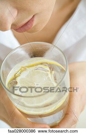 Woman holding glass of water with floating lemon slice, close-up, cropped View Large Photo Image Stock Photograph - Woman holding glass of water with floating lemon slice, close-up, cropped. Fotosearch