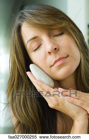 Woman holding pebble against cheek, head tilted, eyes closed, close-up View Large Photo Image Stock Photography - Woman holding pebble against cheek, head tilted, eyes closed, close-up. Fotosearch