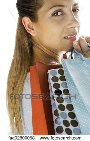 Stock Image - Woman holding shopping bags over shoulder, looking at camera. Fotosearch