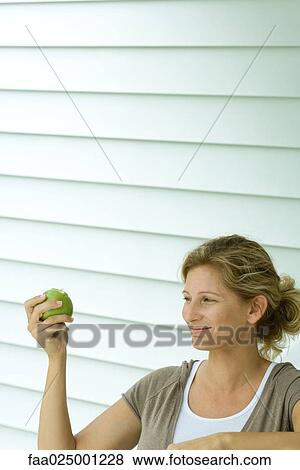 Woman holding up apple and smiling View Large Photo Image Stock Photo - Woman holding up apple and smiling. Fotosearch
