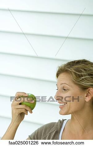 Woman holding up apple and smiling View Large Photo Image Stock Photograph - Woman holding up apple and smiling. Fotosearch