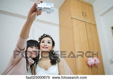 Woman holding up digital camera, photographing self with bride View Large Photo Image Stock Photography - Woman holding up digital camera, photographing self with bride. Fotosearch
