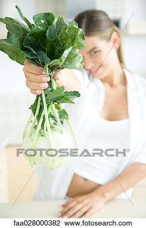 Woman holding up fresh kohlrabi, smiling at camera View Large Photo Image Stock Image - Woman holding up fresh kohlrabi, smiling at camera. Fotosearch