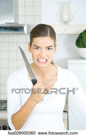 Woman holding up kitchen knife, clenching teeth, looking at camera, portrait View Large Photo Image Stock Image - Woman holding up kitchen knife, clenching teeth, looking at camera, portrait. Fotosearch