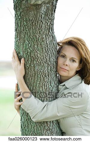 Woman hugging tree trunk, portrait View Large Photo Image Stock Image - Woman hugging tree trunk, portrait. Fotosearch