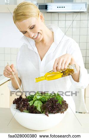 Woman in kitchen, pouring olive oil on large salad View Large Photo Image Stock Image - Woman in kitchen, pouring olive oil on large salad. Fotosearch