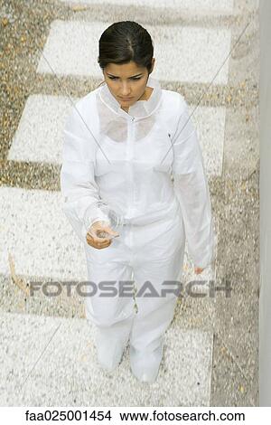 Woman in protective suit walking, carrying light bulb, high angle view View Large Photo Image Picture - Woman in protective suit walking, carrying light bulb, high angle view. Fotosearch