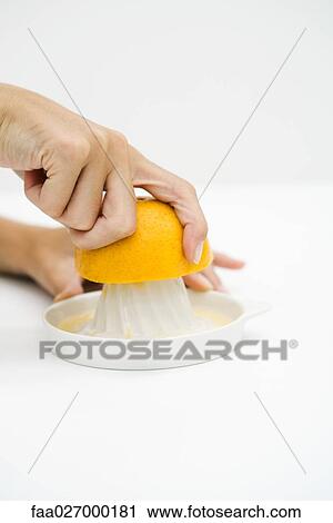 Stock Image - Woman juicing orange, cropped view, close-up. Fotosearch