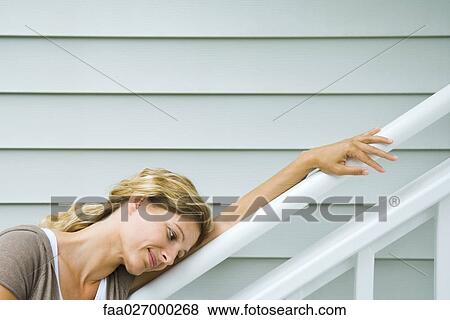 Woman leaning against railing, head resting on arm, smiling, side view View Large Photo Image Stock Photo - Woman leaning against railing, head resting on arm, smiling, side view. Fotosearch