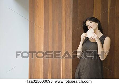 Woman leaning against wall, holding fan in front of face, looking up View Large Photo Image Stock Photography - Woman leaning against wall, holding fan in front of face, looking up. Fotosearch