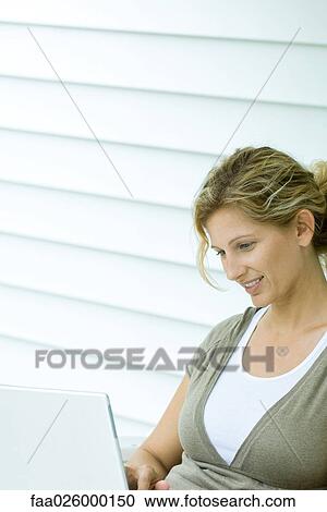 Woman looking down at laptop computer, smiling, cropped View Large Photo Image Stock Image - Woman looking down at laptop computer, smiling, cropped. Fotosearch