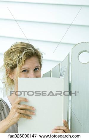 Woman looking over book at camera, close-up View Large Photo Image Stock Photo - Woman looking over book at camera, close-up. Fotosearch