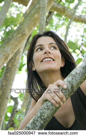 Stock Photo - Woman looking over branch, low angle view. Fotosearch