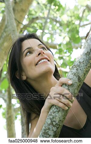 Stock Photo - Woman looking over branch, low angle view. Fotosearch