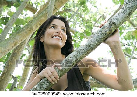 Woman looking over branch, low angle view View Large Photo Image Stock Photo - Woman looking over branch, low angle view. Fotosearch