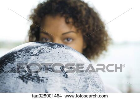 Woman looking over globe at camera, cropped view View Large Photo Image Picture - Woman looking over globe at camera, cropped view. Fotosearch