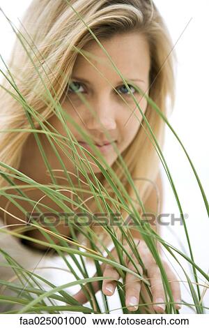 Stock Image - Woman looking through tall grass. Fotosearch