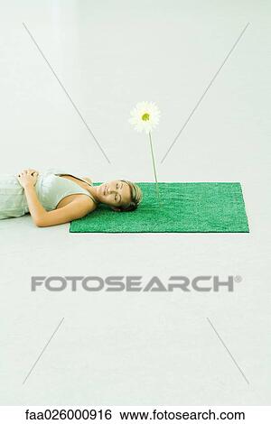 Woman lying on artificial turf next to gerbera daisy, eyes closed View Large Photo Image Stock Photograph - Woman lying on artificial turf next to gerbera daisy, eyes closed. Fotosearch