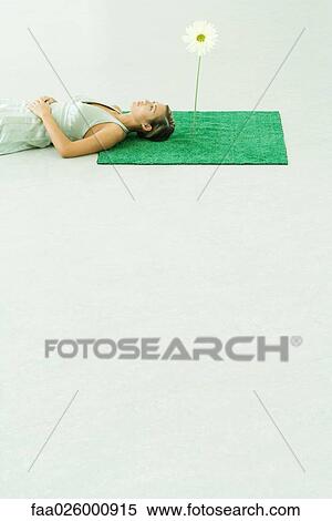 Woman lying on artificial turf next to gerbera daisy, looking up View Large Photo Image Stock Photography - Woman lying on artificial turf next to gerbera daisy, looking up. Fotosearch