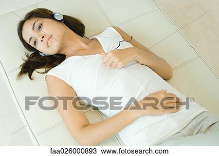 Woman lying on back, listening to headphones, high angle view View Large Photo Image Stock Image - Woman lying on back, listening to headphones, high angle view. Fotosearch