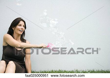 Woman making bubbles with bubble wand View Large Photo Image Stock Image - Woman making bubbles with bubble wand. Fotosearch