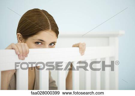 Stock Photo - Woman peeking over side of crib at camera. Fotosearch