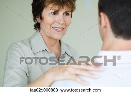Woman placing hand on adult son's shoulder, over the shoulder view View Large Photo Image Stock Image - Woman placing hand on adult son's shoulder, over the shoulder view. Fotosearch