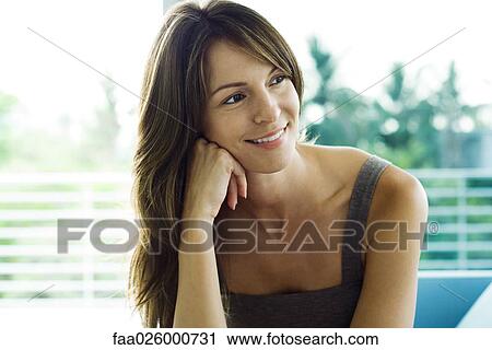 Woman resting head on hand, looking away, smiling View Large Photo Image Stock Image - Woman resting head on hand, looking away, smiling. Fotosearch