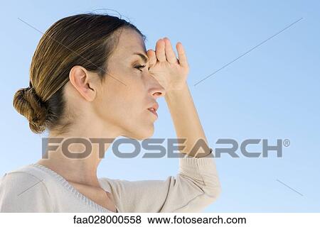 Woman shading eyes, looking away, low angle view View Large Photo Image Stock Photo - Woman shading eyes, looking away, low angle view. Fotosearch