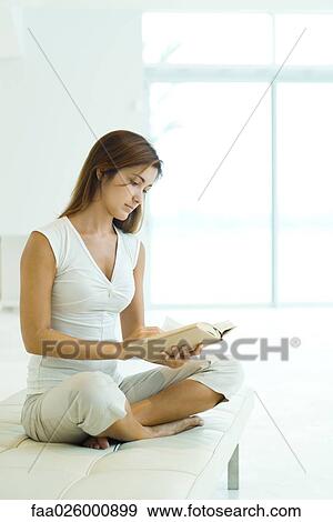 Woman sitting crosslegged, reading book, full length View Large Photo Image Stock Photo - Woman sitting crosslegged, reading book, full length. Fotosearch