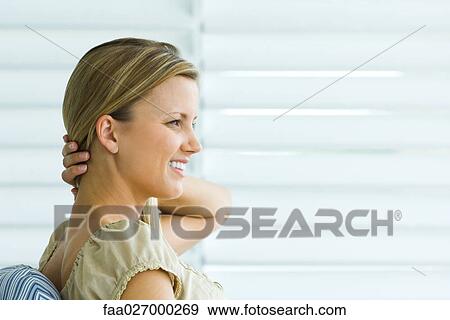 Stock Photo - Woman sitting, hand in hair, looking away, side view. Fotosearch