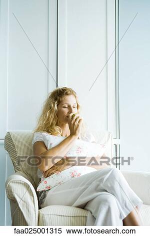 Woman sitting in armchair, smelling apple, eyes closed View Large Photo Image Stock Photography - Woman sitting in armchair, smelling apple, eyes closed. Fotosearch