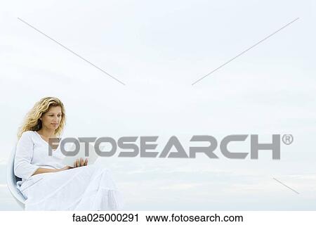 Woman sitting in chair outdoors, reading book View Large Photo Image Stock Image - Woman sitting in chair outdoors, reading book. Fotosearch
