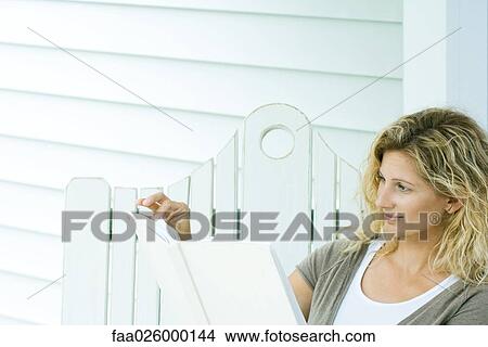Picture - Woman sitting on bench, reading book, cropped view. Fotosearch