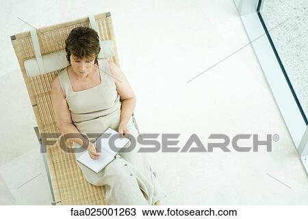 Woman sitting on lounge chair writing in diary, high angle view View Large Photo Image Stock Image - Woman sitting on lounge chair writing in diary, high angle view. Fotosearch