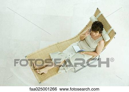 Woman sitting on lounge chair writing in diary, high angle view View Large Photo Image Stock Photograph - Woman sitting on lounge chair writing in diary, high angle view. Fotosearch