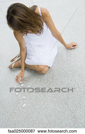 Woman sitting on the ground arranging pebbles View Large Photo Image Stock Photo - Woman sitting on the ground arranging pebbles. Fotosearch