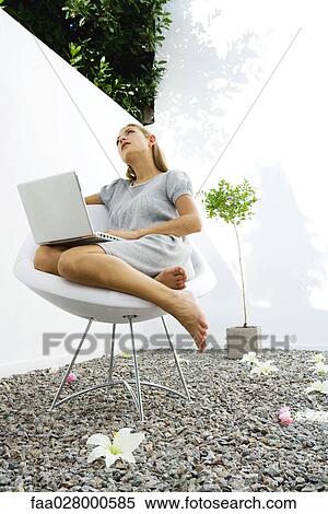 Woman sitting outdoors using laptop View Large Photo Image Stock Photography - Woman sitting outdoors using laptop. Fotosearch