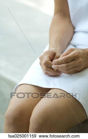 Woman sitting with hands on legs, cropped view View Large Photo Image Stock Photo - Woman sitting with hands on legs, cropped view. Fotosearch